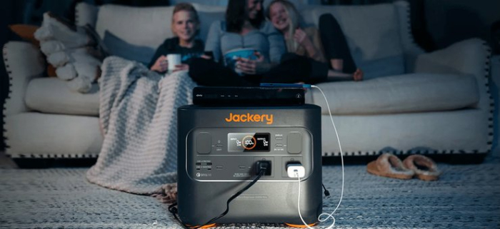 Жінка з дітьми сидить на дивані перед зарядною станцією Jackery